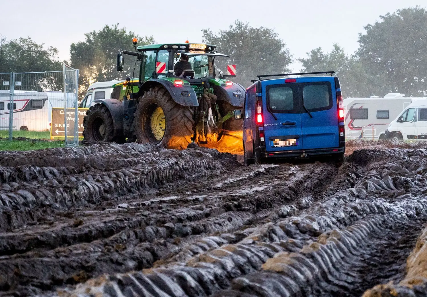 Gribbohm: Autos werden mithilfe eines Traktors auf das Gelände des Heavy-Metal-Festivals 2023 in Schleswig-Holstein in Wacken durch den Schlamm gezogen.