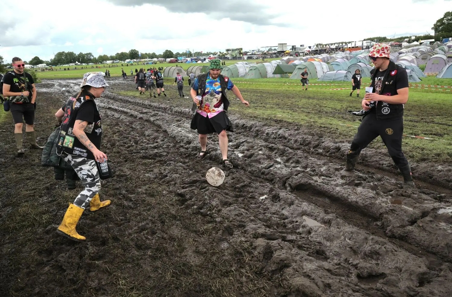 Schleswig-Holstein, Wacken: Metal-Fans spielen auf dem vom Regen aufgeweichten und schlammigen Festivalgelände mit einem Ball. Das Wacken Open-Air (WOA) gilt als größtes Heavy-Metal-Festival der Welt.