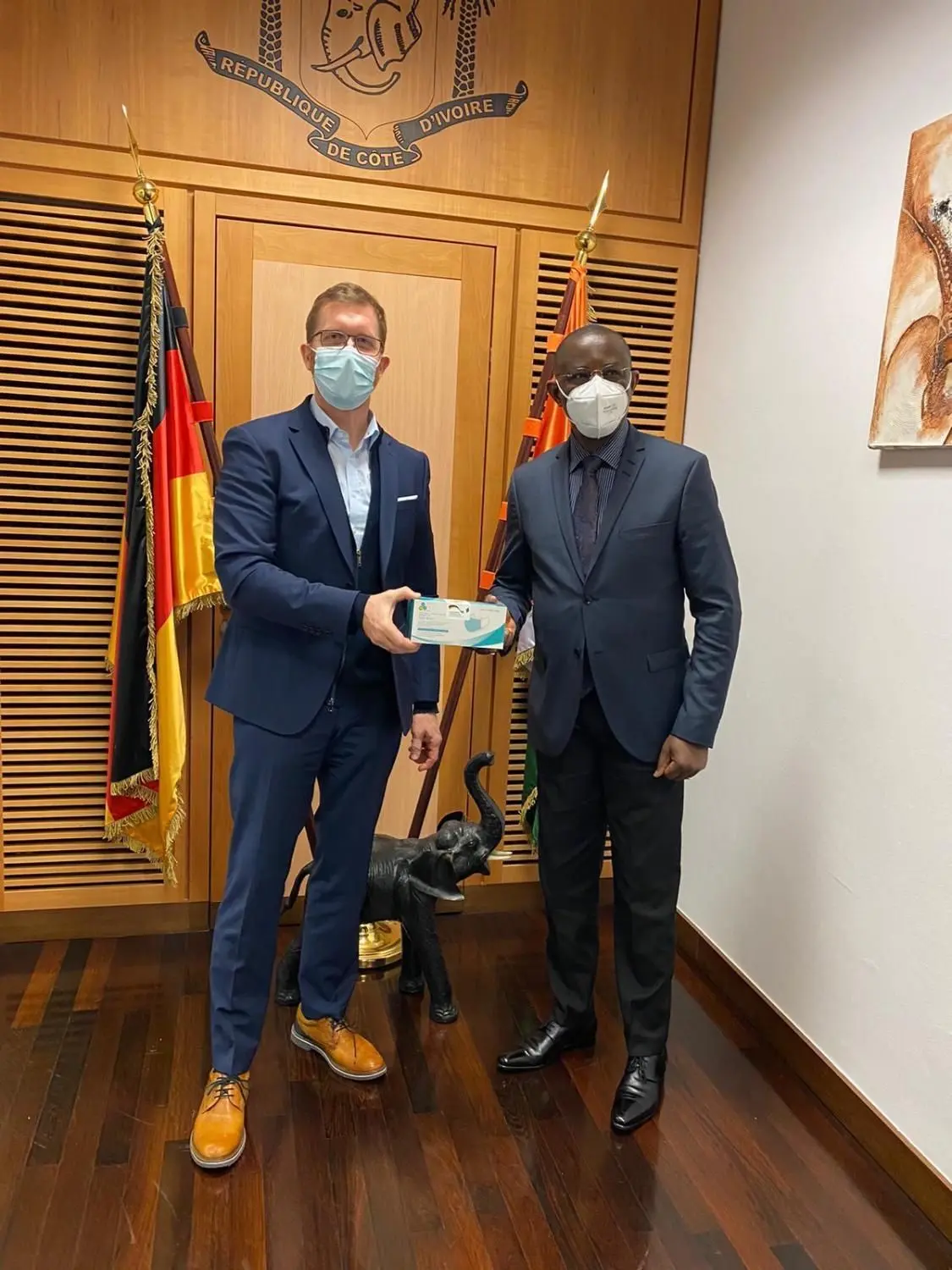 Der Geschäftsführer des Chemnitzer Unternehmens authentic.network, Frank Theeg (l), und der Botschafter der Elfenbeinküste, Philippe Mangou, präsentieren in der ivorischen Botschaft in Berlin Covid-19-Schutzausrüstung, die mit einem intelligenten Code vor Fälschungen geschützt ist.