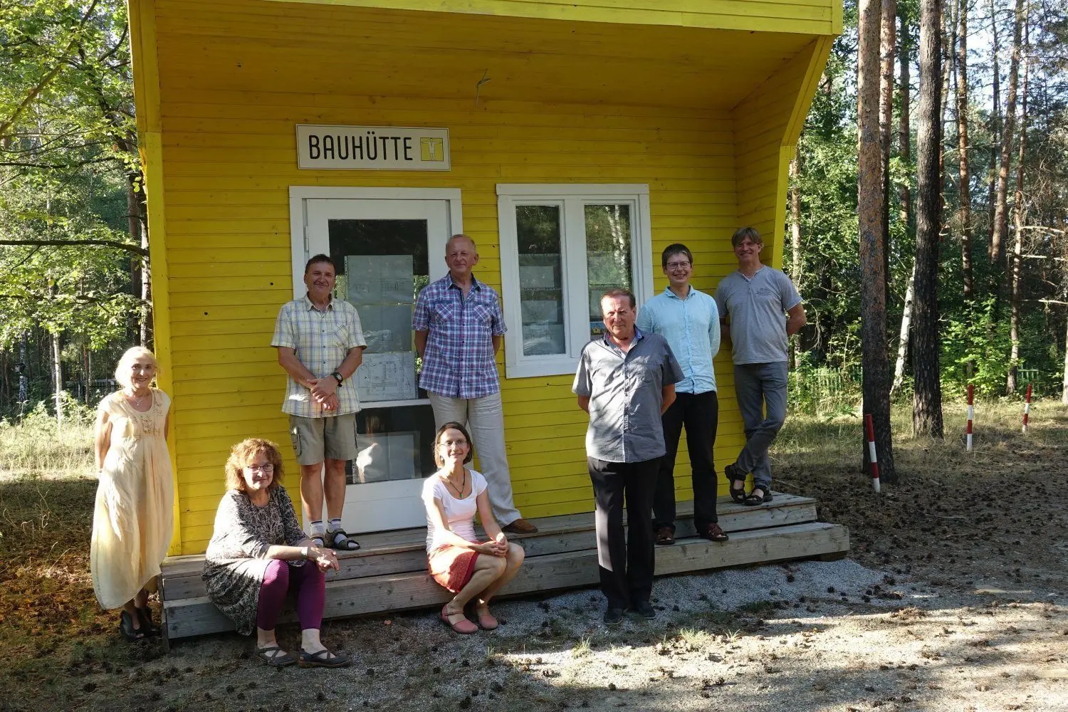 Die Mitglieder des Stiftungsrates haben vor der Bauhütte, die auf dem Gelände der Station steht, Aufstellung genommen.