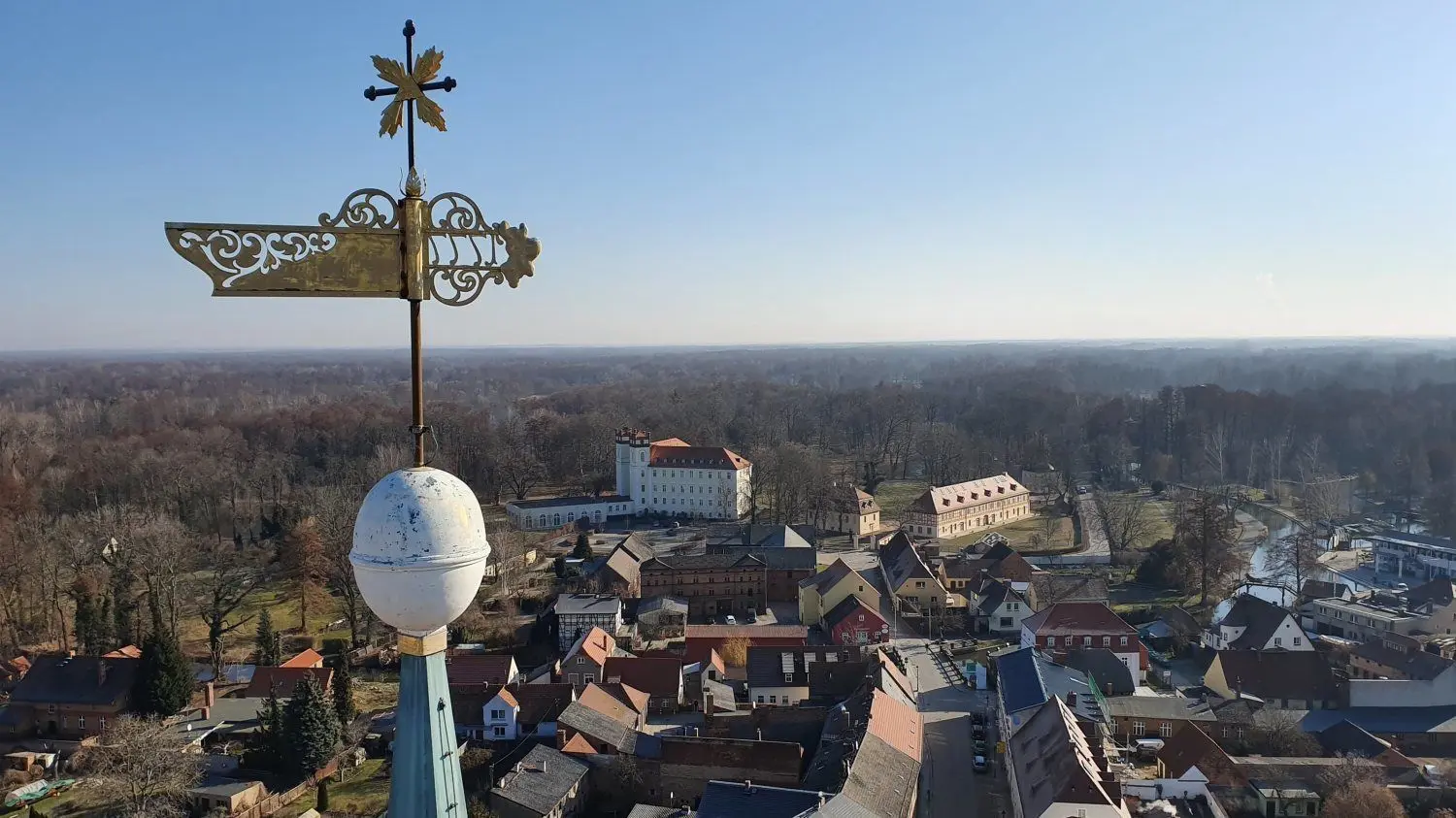 Die Turmbekrönung der Lübbenauer Nikolaikirche, fotografiert von der Kran-Arbeitsbühne aus. Im Hintergrund sind das Schloss mit Kanzlei und Marstall gut zu erkennen.