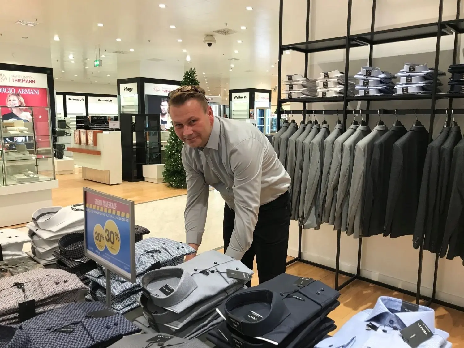 Abteilungsleiter Karsten Schmidt sortiert Hemden im Erdgeschoss des Aachener Modehauses in Cottbus. Das ehemalige Galeria-Warenhaus in der Innenstadt hat wieder geöffnet. Allerdings ist das Angebot eingeschränkt.