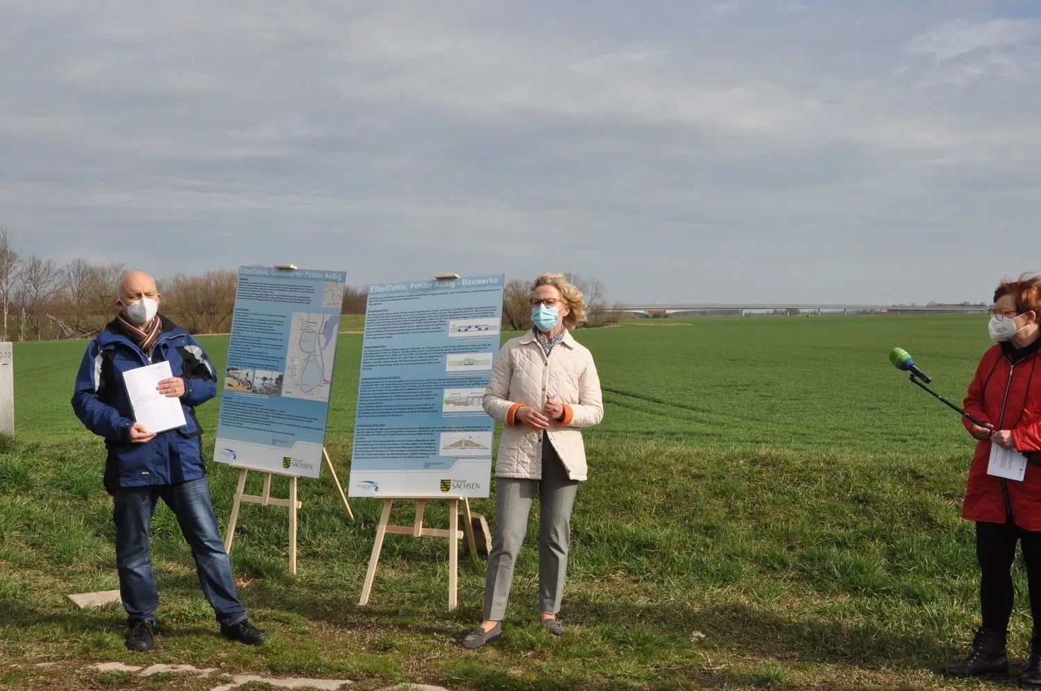 Die Präsidentin der Landesdirektion Sachsen, Regina Kraushaar, übergibt den Planfeststellungsbeschluss an Heinz Gräfe, Geschäftsführer der Landestalsperrenverwaltung. Im Hintergrund ist die Mühlberger Elbebrücke zu erkennen.