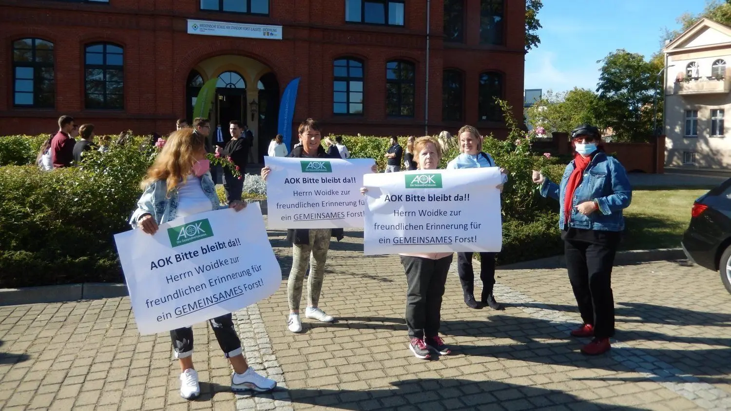 Bei Eröffnung der neuen Pflegeschule in Forst protestieren Einwohner gegen die geplante Schließung der AOK-Geschäftsstelle.