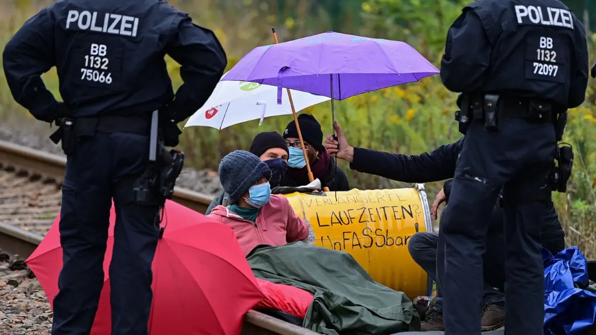 19. September 2022: Kraftwerksbesetzer blockieren eine Gleisverbindung für den Transport von Braunkohle zum Kraftwerk Jänschwalde.
19.09.2022, Brandenburg, Teichland: Klimaaktivisten blockieren eine Gleisverbindung für den Transport von Braunkohle zum Kraftwerk Jänschwalde. Klimaaktivisten sind am Montagmorgen auf das Gelände des Kohlekraftwerks in Jänschwalde im Süden Brandenburgs eingedrungen. Die Polizei sei mit mehreren Kräften im Einsatz, sagte eine Sprecherin des Polizeipräsidiums Brandenburg. Die Gruppe «Unfreiwillige Feuerwehr» teilte mit, etwa 40 Menschen befänden sich auf dem Gelände und blockierten unter anderem den Kohlebunker und die Gleisverbindungen zum Kraftwerk. Foto: Patrick Pleul/dpa +++ dpa-Bildfunk +++