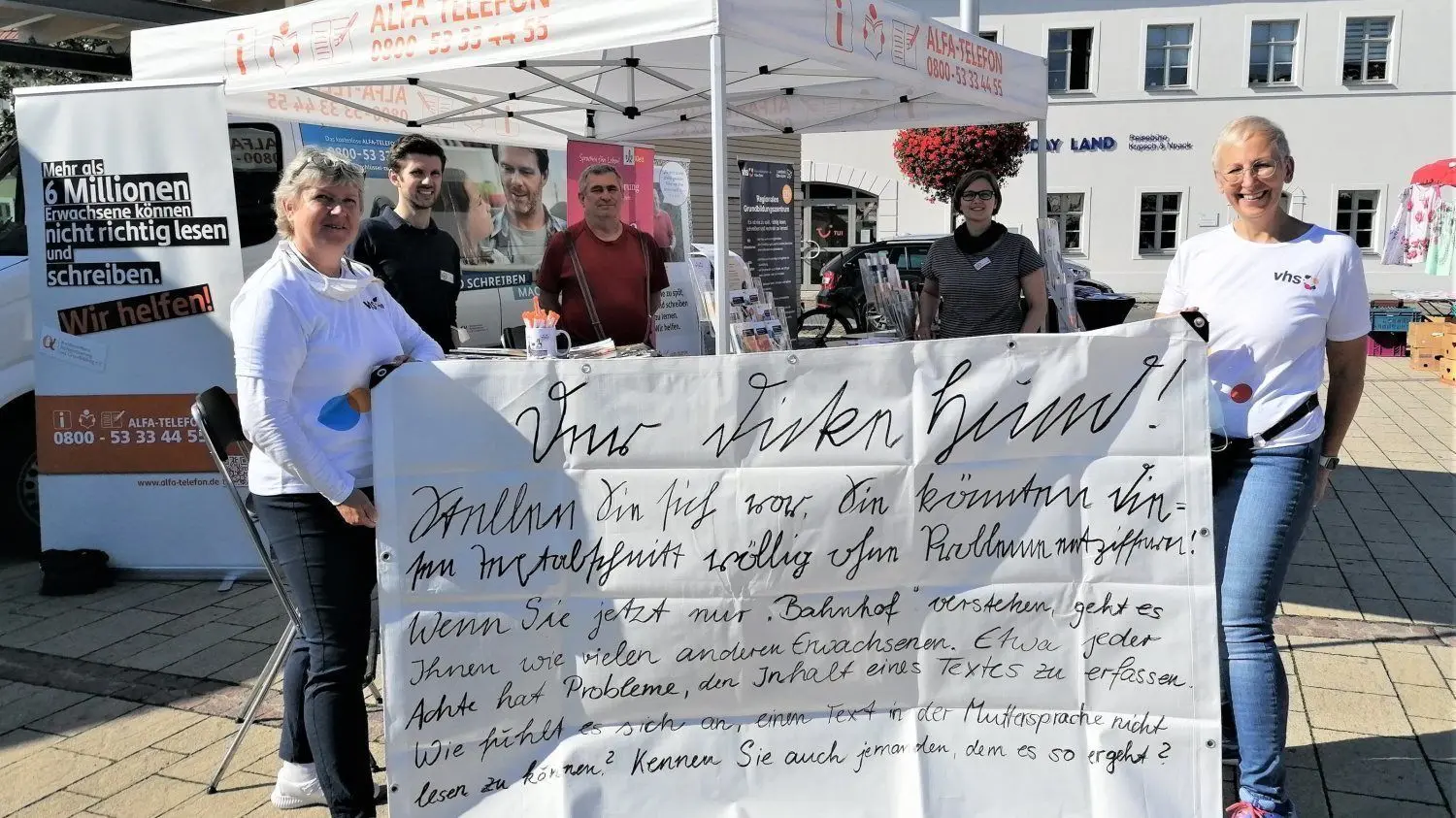 Sabine Rau (r.), Projektleiterin des Grundbildungszentrums in Elsterwerda, und ihre Mitarbeiterin Birgit Teichmann halten ein Transparent in die Kamera, das alles darüber sagt, wie es Menschen mit großen Lese- und Schreibschwierigkeiten im Alltag ergeht.