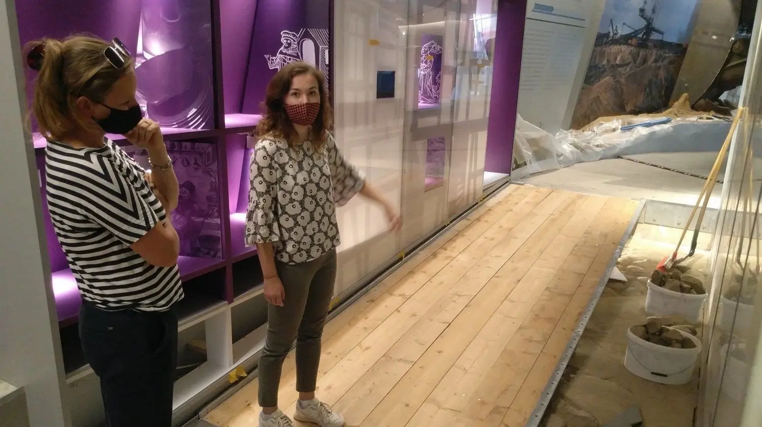 Kim Nora Magdeburg (r.), projektleitende Innenarchitektin des Büros Dr. Hermanns, dem Ausstellungsgestalter aus Münster, erläutert einige Neuheiten während des Ausstellungsrundganges. Sina Steinführer von der Stadt Vetschau schaut sich das geplante Farbkonzept auf dem Boden an.