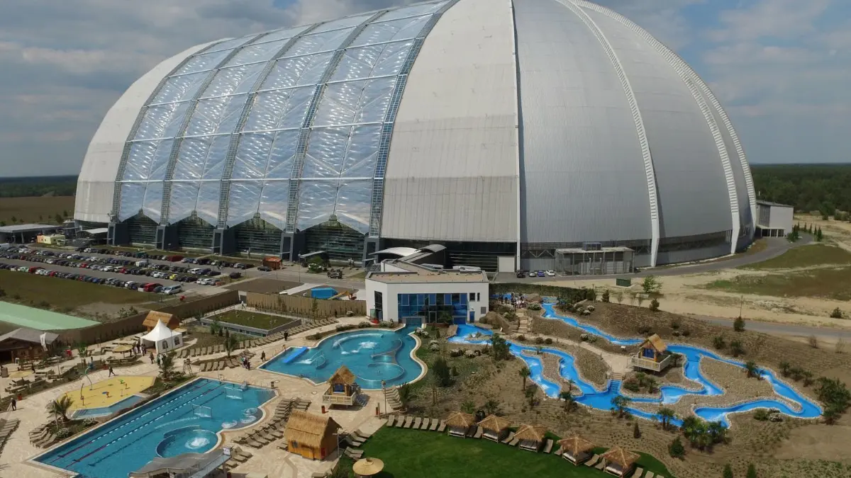Dort wo einst Luftschiffe gebaut werden sollten, locken jetzt tropische Landschaften. Das Tropical Islands wurde zum touristischen Anziehungspunkt.
Ein 35.000 Quadratmeter großer Open Air Wasserpark, aufgenommen am 20.05.2016 vor der Kulisse des Resorts "Tropical Island" in Krausnick (Brandenburg). Nach der heutigen offiziellen Eröffnung stehen nach Angaben des Unternehmens nun 100.000 Quadratmeter Erholungsfläche zur Verfügung. Im Jahr 2015 wurde das Resort von über einer Million Gäste besucht. (Aufnahme mit Drohne) Foto: Ralf Hirschberger/dpa +++(c) dpa - Bildfunk+++ |