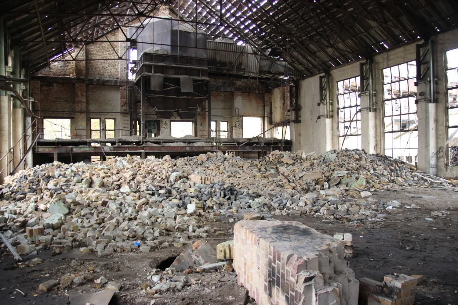 Blick in das Innere der Produktionshalle der Haidemühler Hütte. Außer Ruinen, losen Steinen und Müll erinnert kaum noch etwas an die Glasproduktion.