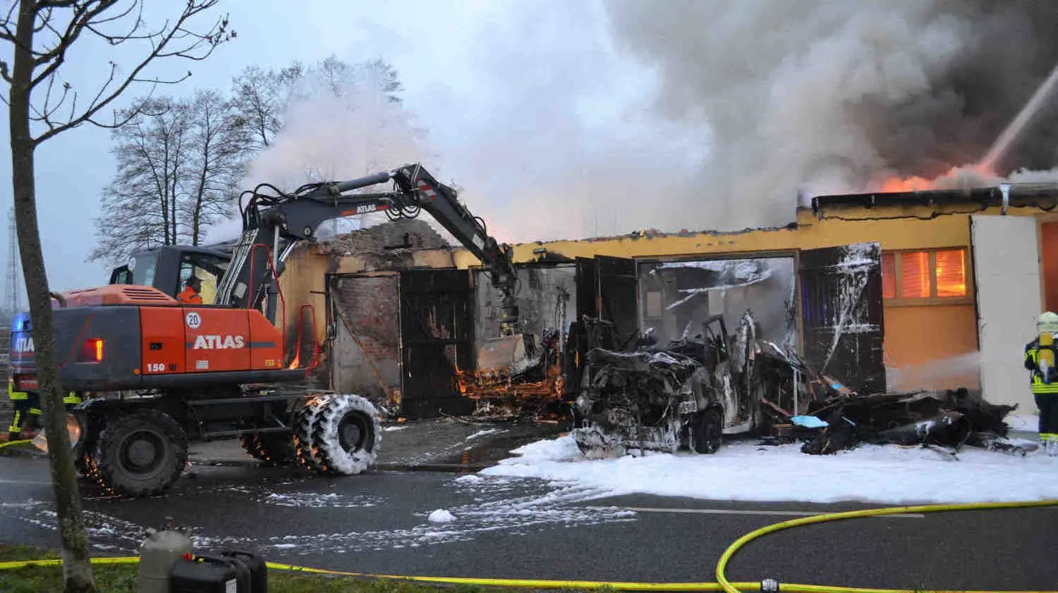 Ein Bagger unterstützt die Arbeiten der Feuerwehr in Hoyerswerda am Morgen.