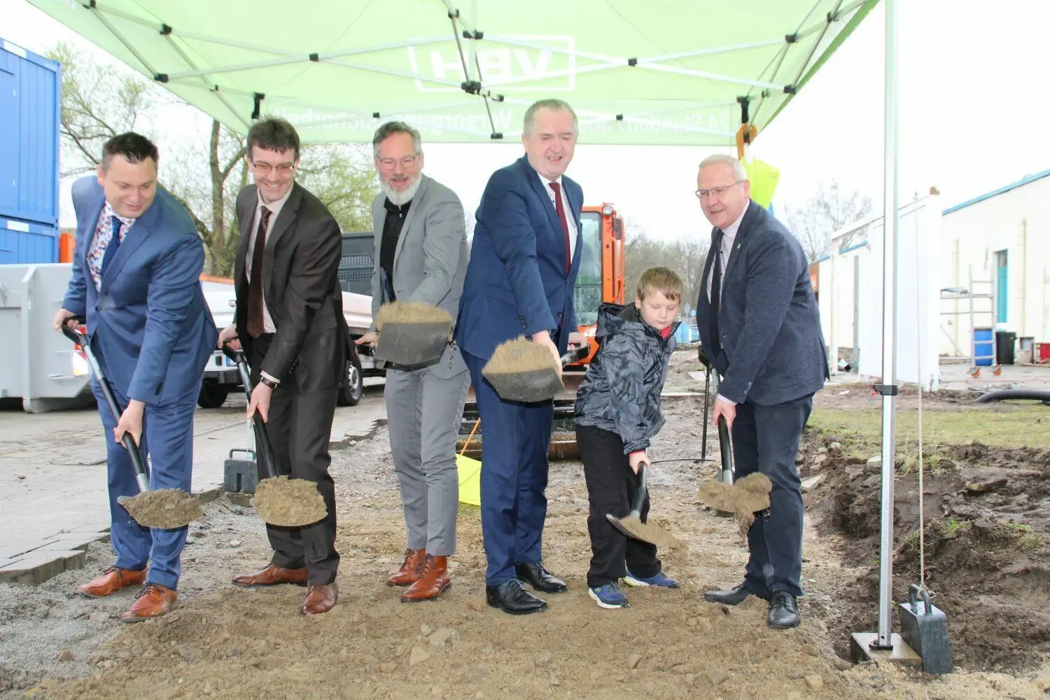 Fünf große und ein kleiner Mann vollziehen den ersten Spatenstich für den Umbau des Lausitzbades Hoyerswerda. Zwischen dem Staatsminister Thomas Schmidt (3.v.r.) und OB Torsten Ruban-Zeh (r.) schaufelt auch dessen Sohn Oscar für den symbolischen Baustart.