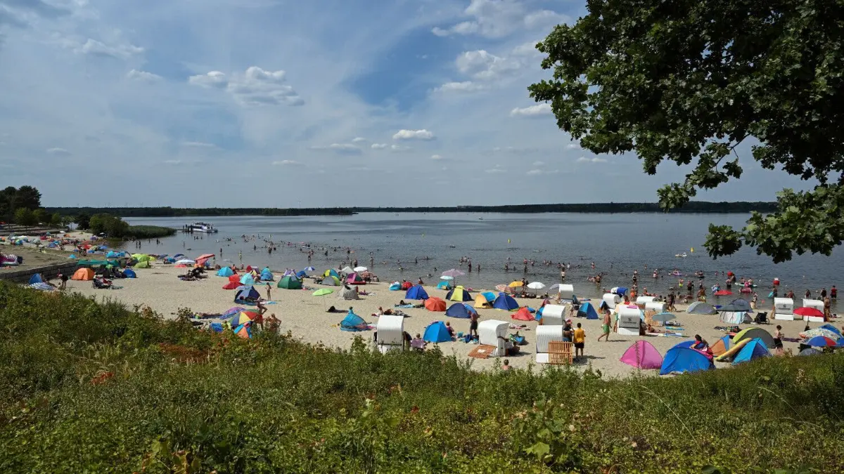 Der Senftenberger See, der auch als Speicherbecken dient, hat nach dem Regen beim Wasserstand satte fünf Zentimeter zugelegt.
04.08.2022, Brandenburg, Senftenberg: Ausflugsgäste baden und sonnen sich am Badestrand Großkoschen am Senftenberger See. Der künstliche See war bis 1972 durch die Flutung eines ehemaligen Braunkohletagebau enstanden und ist bis zu 25 Meter tief. Als Naherholungsgebiet erfreut sich der See bei Touristen großer Beliebtheit. (zu dpa-Umfrage Tourismusgebiete·) Foto: Soeren Stache/dpa +++ dpa-Bildfunk +++