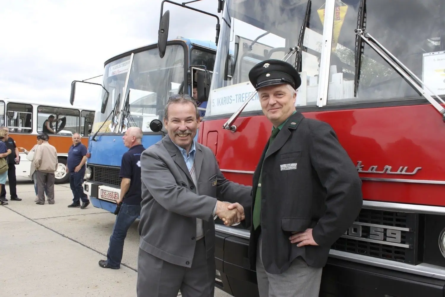 Echte Fans von Ikarus-Fahrzeugen: Detlef Gossow (64) und Ronald Lehmann (50) begrüßen sich beim Ikarus-Treffen auf dem Betriebshof der Verkehrsbetriebe Hoyerswerda vor einem Ikarus des Typs 250. Beide tragen alte Busfahrer-Uniformen.