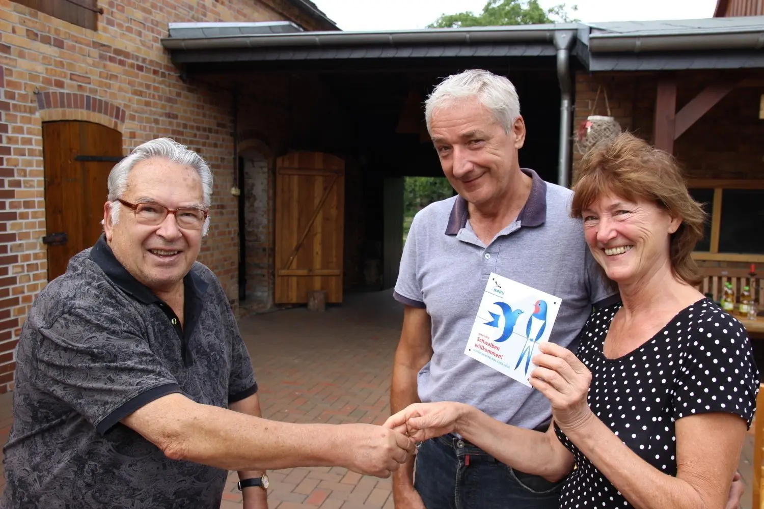 Hier überreicht Klaus Uhl (l.) vom Nabu-Regionalverband Senftenberg die Schwalben-willkommen-Plakette an Hans-Joachim und Beate Kupz. ⇥