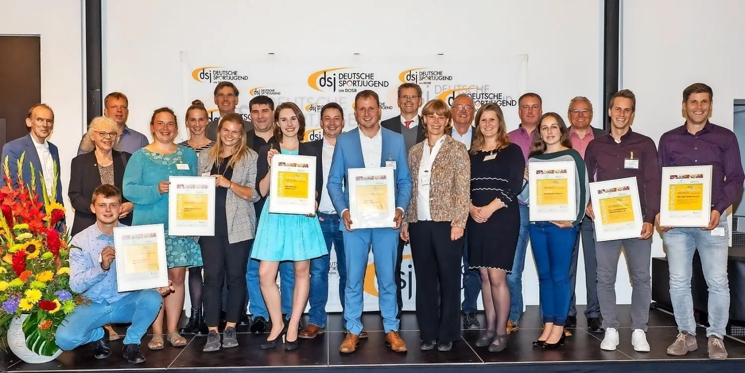 Sieger des Zukunftspreises 2019 der Deutschen Sportjugend ist der Sportclub Hoyerswerda: Fachbereichsleiter Lars Bauer (blauer Anzug) und rechts daneben SC-Geschäftsführerin Daniela Fünfstück nehmen die Auszeichnung in Frankfurt am Main freudestrahlend entgegen.⇥
