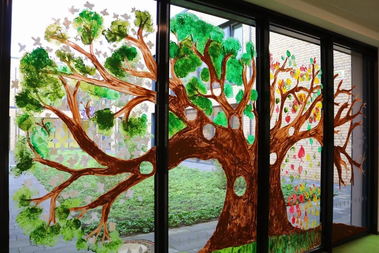 Der großzügige Hortbereich ist ein Wohlfühlort für die Grundschüler. Toben und Kreativsein wird großgeschrieben. Dieses Baum-Fensterbild gehört zu den Ergebnissen.