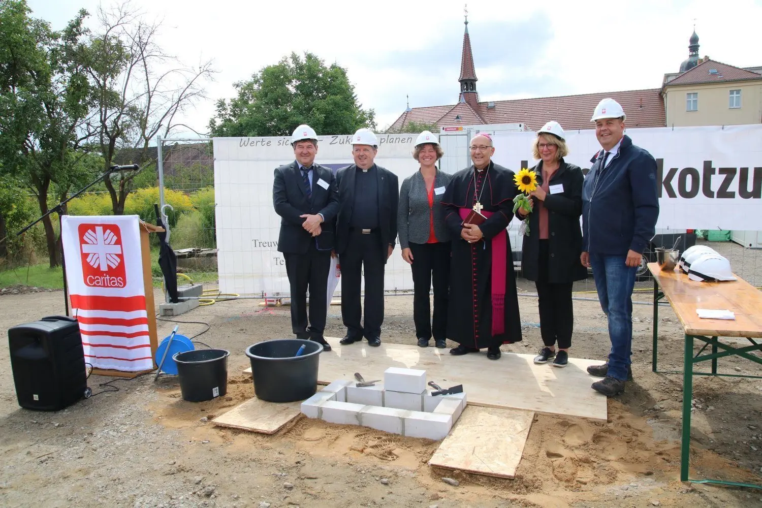 Gruppenbild am Grundstein: Diözesancaritasdirektor Bernhard Mones, Pfarrer Udo Jäkel, Vorstandsmitglied Felicitas Baensch, Bischof Wolfgang Ipolt, Bettina Schwarz Referentin für Kinder, Jugend und Familienhilfe, Bürgermeister Lars Kolan