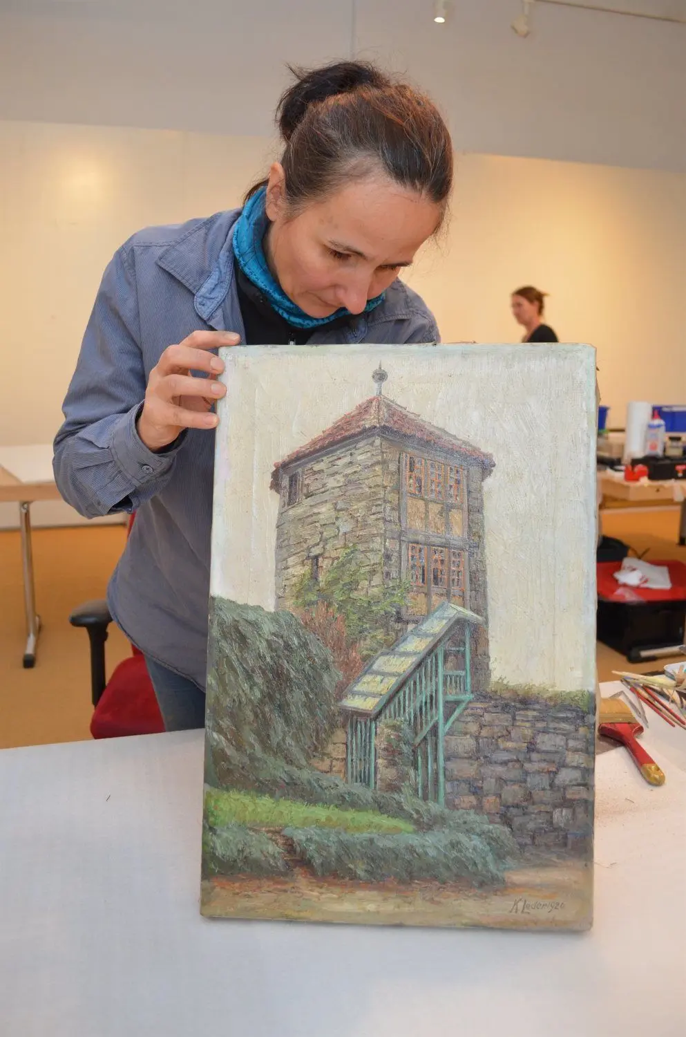 Hoyerswerda: Die Restauratorin Stefanie Matthes-Ehrig bearbeitet ein Bild des Hoyerswerdaer Malers Karl Leder. Unklar ist, wo sich dieser Turm befindet.