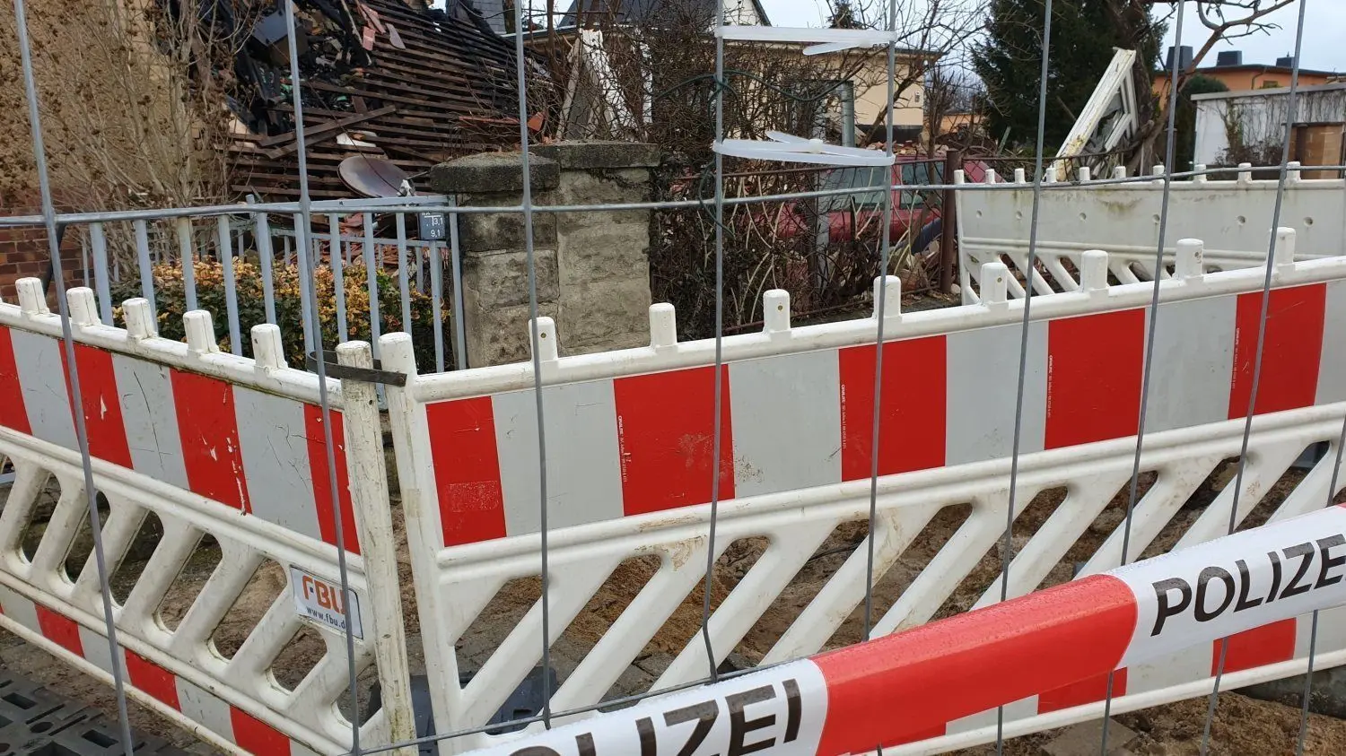 Der Schauplatz des Unglücks an der Schacksdorfer Straße in Finsterwalde 24 Stunden nach dem Großeinsatz der Feuerwehr und vieler weiterer Helfer: Das Grundstück ist mit einem Bauzaun abgesperrt, die Doppelhaushälfte ist völlig zerstört. Auch ein Kleinwagen ist schwer beschädigt worden.