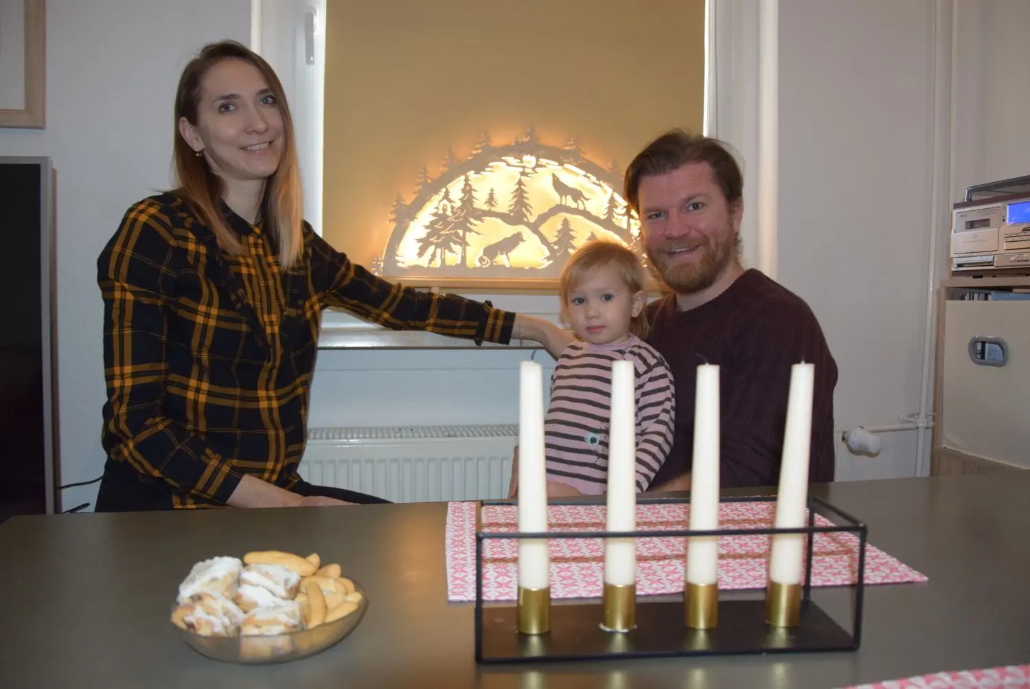 Ein wenig deutsche Weihnachtstradition gibt es auch bei Familie Vukovic: Maryna, Mladen und Stefanie Vukovic posieren vor einem echt Erzgebirgischen Schwibbogen – ein Geschenk.