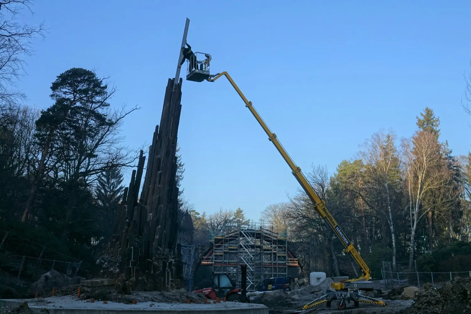 Die Abschluss-Stele wird an der Orgel eingesetzt. Im Hintergrund ist die eingerüstete Rakotzbrücke zu sehen.