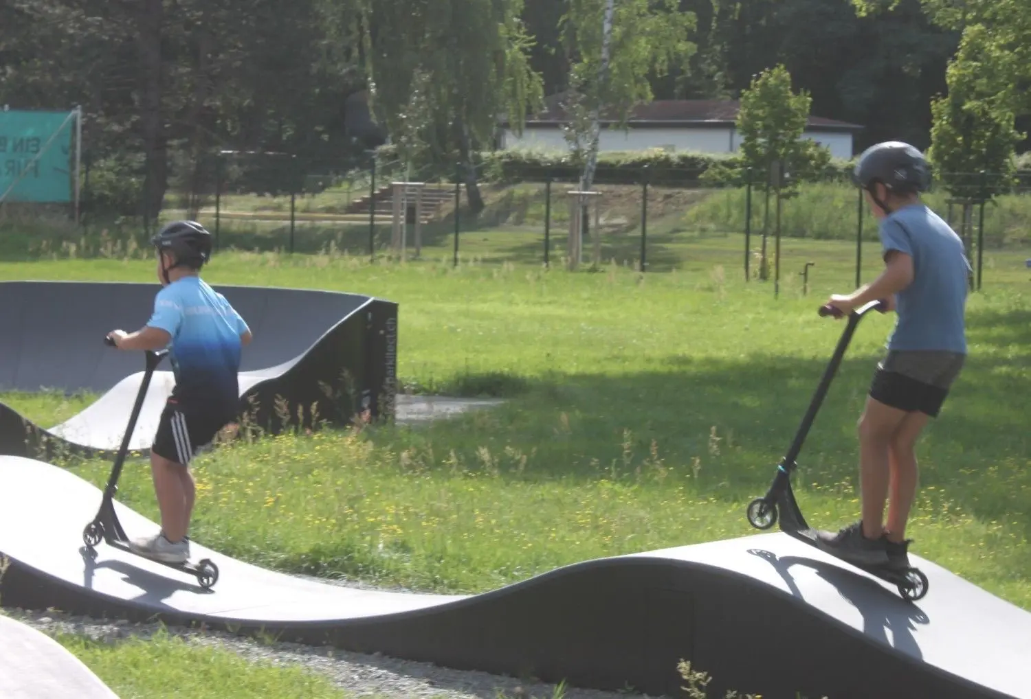 Vorsichtig und mit dem erforderlichen Abstand üben diese beiden Jungen aus dem Hort das Fahren mit dem Roller auf der Pumptrack-Anlage in Herzberg.