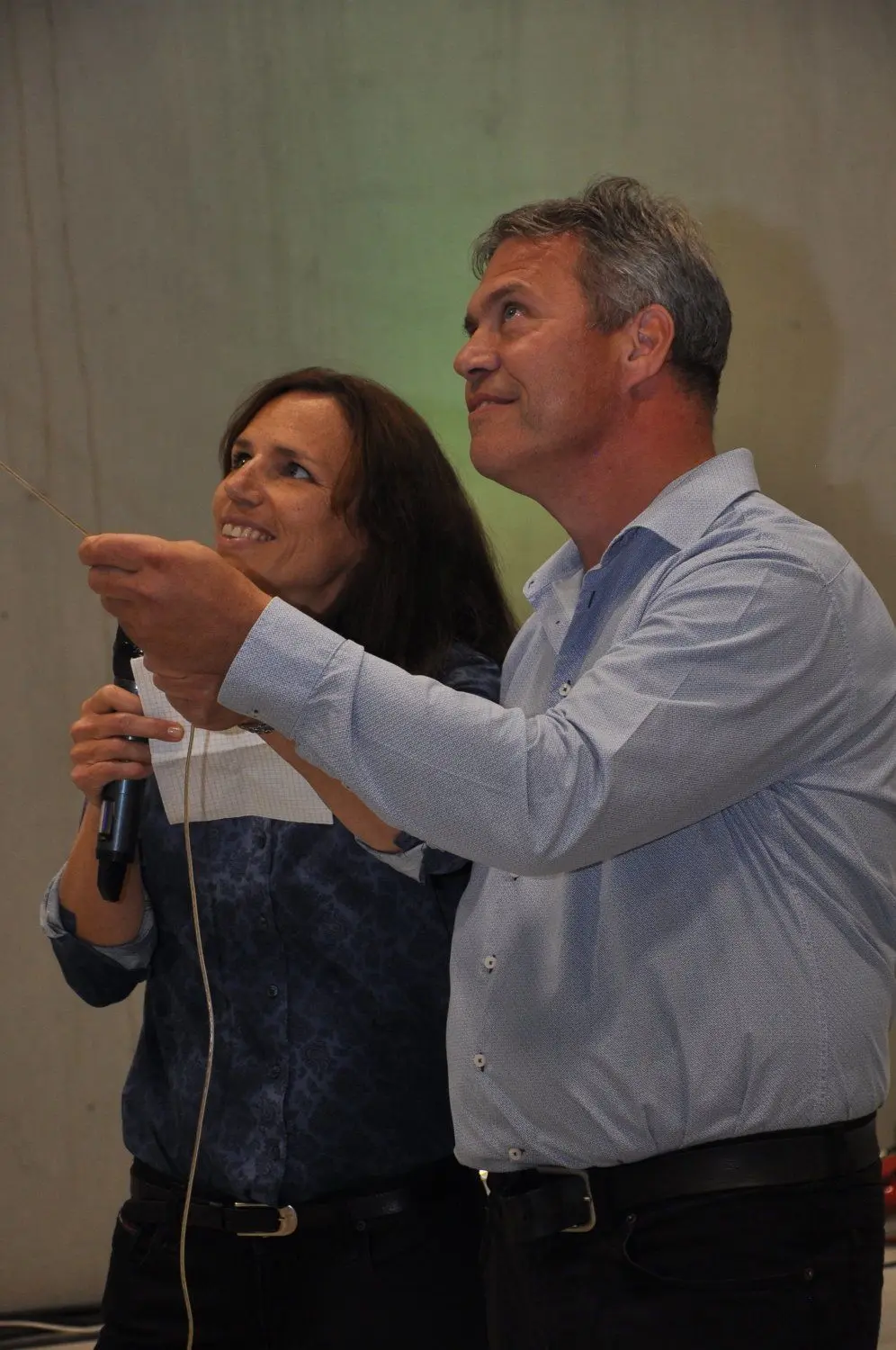 Taufe für das neue Werk der Reiss Büromöbel GmbH Bad Liebenwerda im Gewerbegebiet Lausitz - der künftige Werkleiter am Standort, Henning Stratmann und Sandra Ritz vom Projektteam ziehen am Seil, um die auf einer Traverse unter der Decke stehende Sektflasche so hinunterzuziehen, dass sie gegen eine Wand der Werkhalle knallt; das gelingt, sie zerschellt!