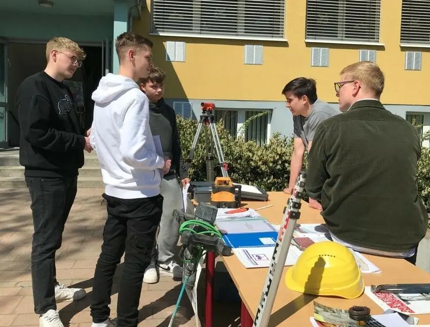 Schüler der 10. Klasse der Clajus-Schule am Stand der Hofmann Bau GmbH im lockeren Gespräch mit Geschäftsführer Konrad Dobra (r.) und Azubi Erich Koschka.