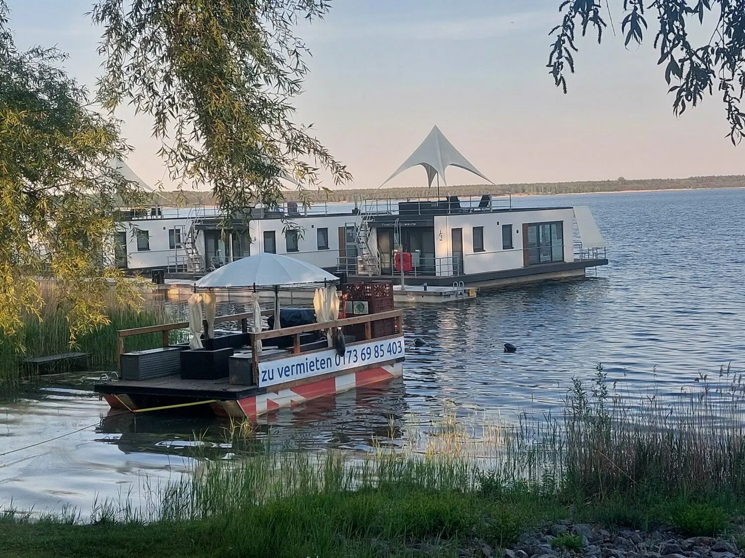 Schwimmende Häuser und ein Partyfloß, was gemietet werden kann: So präsentiert sich derzeit der Gräbendorfer See an der Uferseite Laasow.