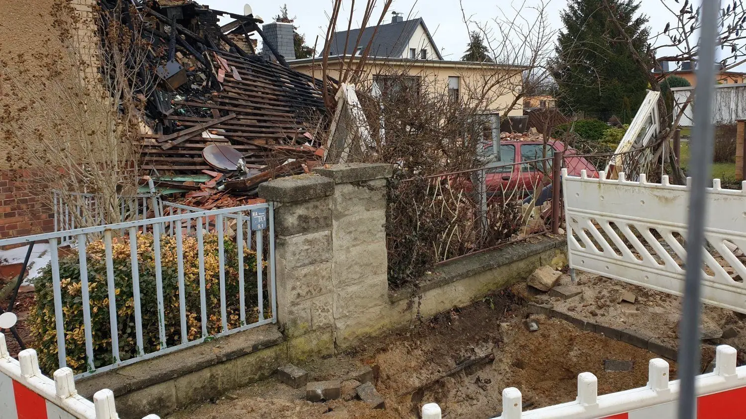 Der Schauplatz des Unglücks an der Schacksdorfer Straße in Finsterwalde 24 Stunden nach dem Großeinsatz der Feuerwehr und vieler weiterer Helfer: Das Grundstück ist mit einem Bauzaun abgesperrt, die Doppelhaushälfte ist völlig zerstört. In dem Loch im Bürgersteig waren Gas und Strom vom Haus abgeklemmt worden.