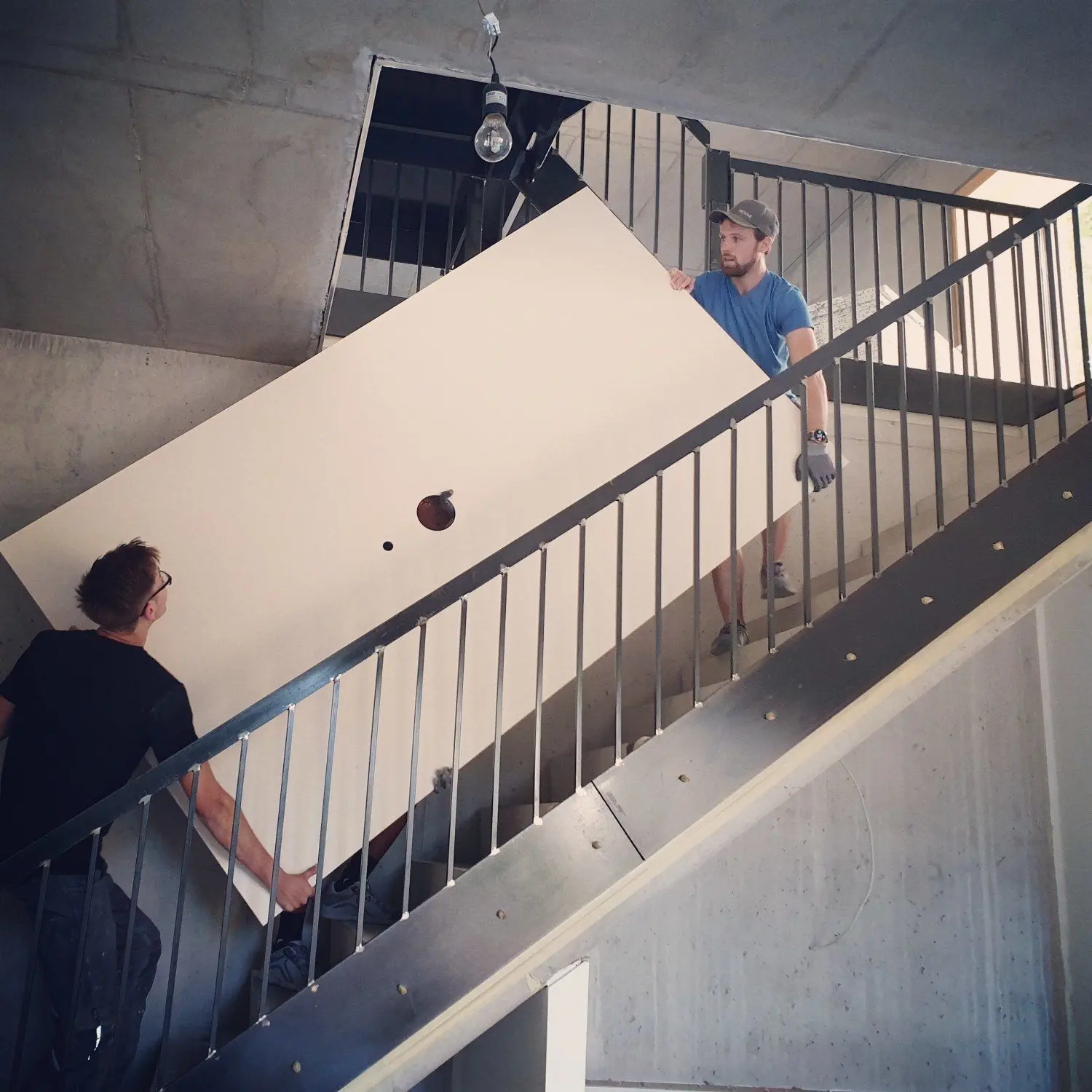 Firmenchef Benjamin Schulz und Azubi Leon Lucas Otto tragen eine großformatige Fliese (circa 1,5 mal 3 Meter)  zum Einsatzort.