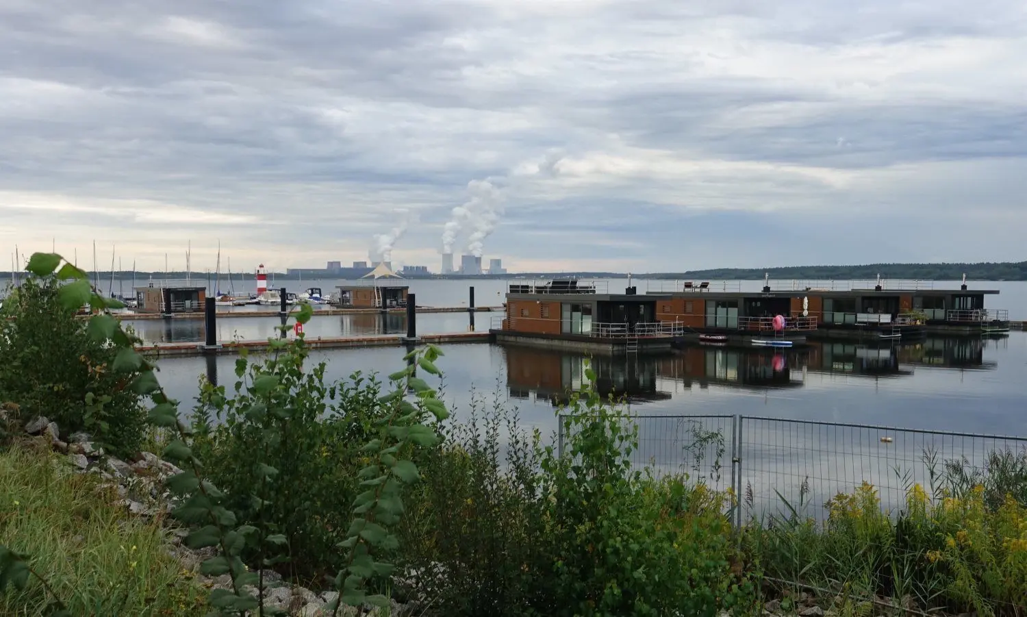 Blick auf die schwimmenden Häuser an der Marina Klitten. Im Hintergrund ist das Kraftwerk Boxberg zu sehen.