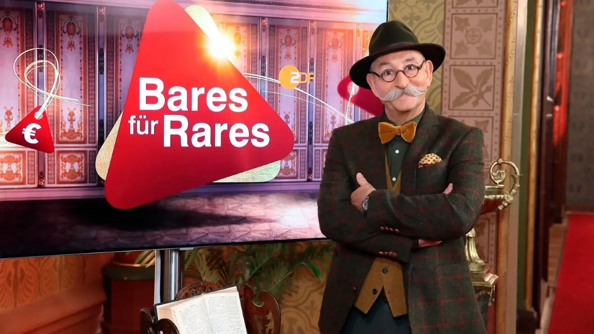 „Bares für Rares“-Moderator Horst Lichter sorgt beim ZDF seit mehr als zehn Jahren für hohe Einschaltquoten.
Moderator Horst Lichter steht neben dem Logo der Sendung «Bares für Rares» (undatierte Aufnahme). Die Trödelshow hat dem ZDF den klaren TV-Quotensieg am 27.11.2019 beschert. (zu dpa "Antiquitätenshow «Bares für Rares» bringt ZDF den Quotensieg") +++ dpa-Bildfunk +++