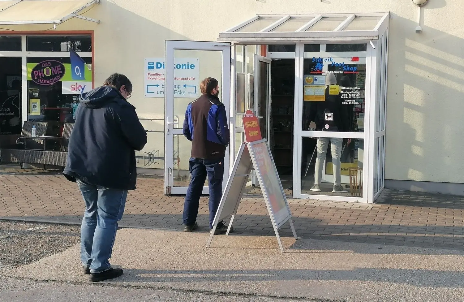 Ein normaler Anblick in der Corona-Pandemie: Vor der Postfiliale in Elsterwerda, Packhofstraße 2, stehen die Kunden auf der Straße Schlange.
