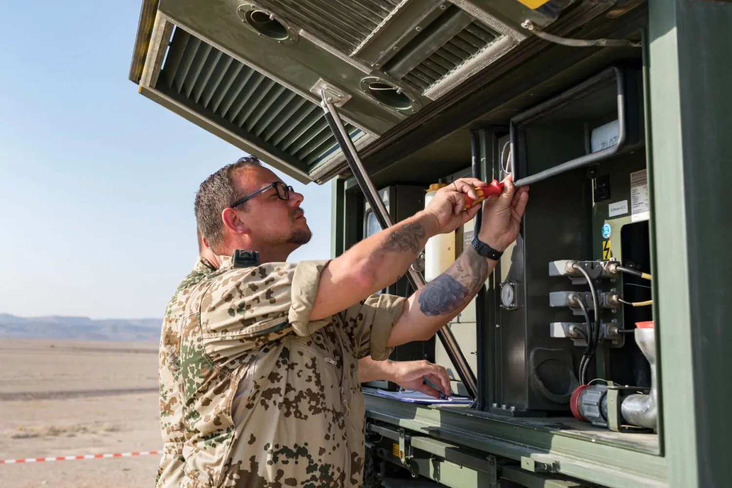 Oberfeldwebel Daniel Lenhart bei der Überprüfung der SatCom-Anlage. Auch das technische Equipment hat unter der Hitze gelitten.
