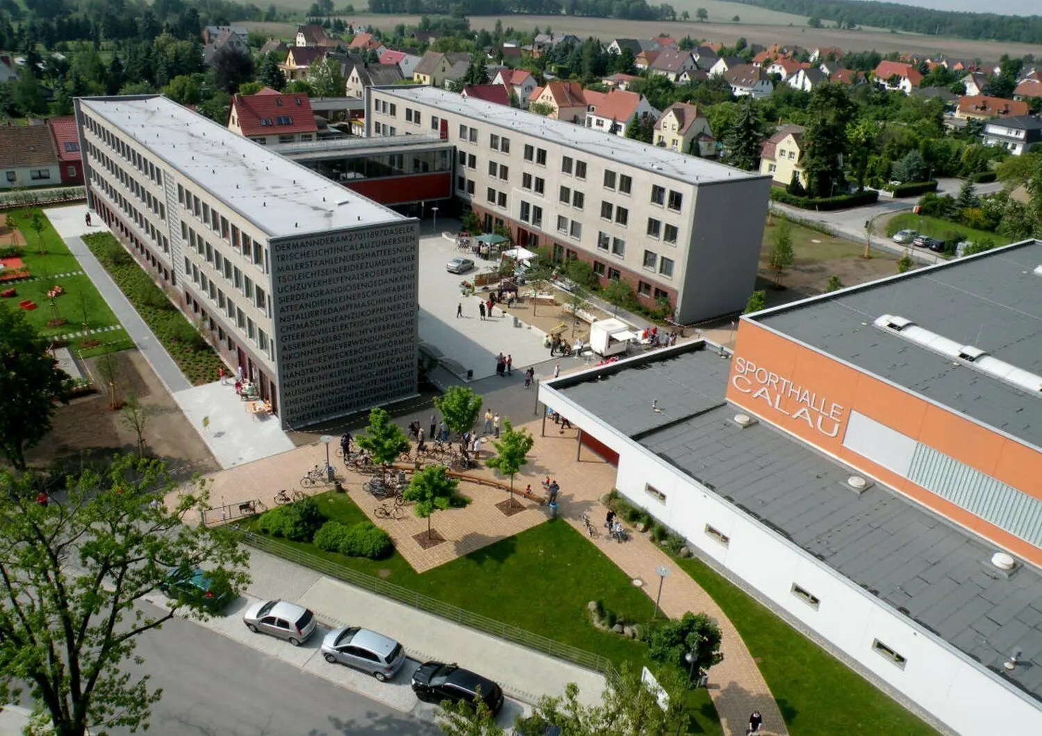 Luftaufnahme der Calauer Oberschule mit angrenzender Sporthalle. Die Sanierung vom Robert-Schlesier-Haus (H-förmiger Baukörper) ist nun abgeschlossen. Von Mitte 2019 bis Anfang 2020 wurde zunächst Haus 1 saniert (linker Flügel), inzwischen ist auch Haus 2 fertiggestellt (rechter Flügel).