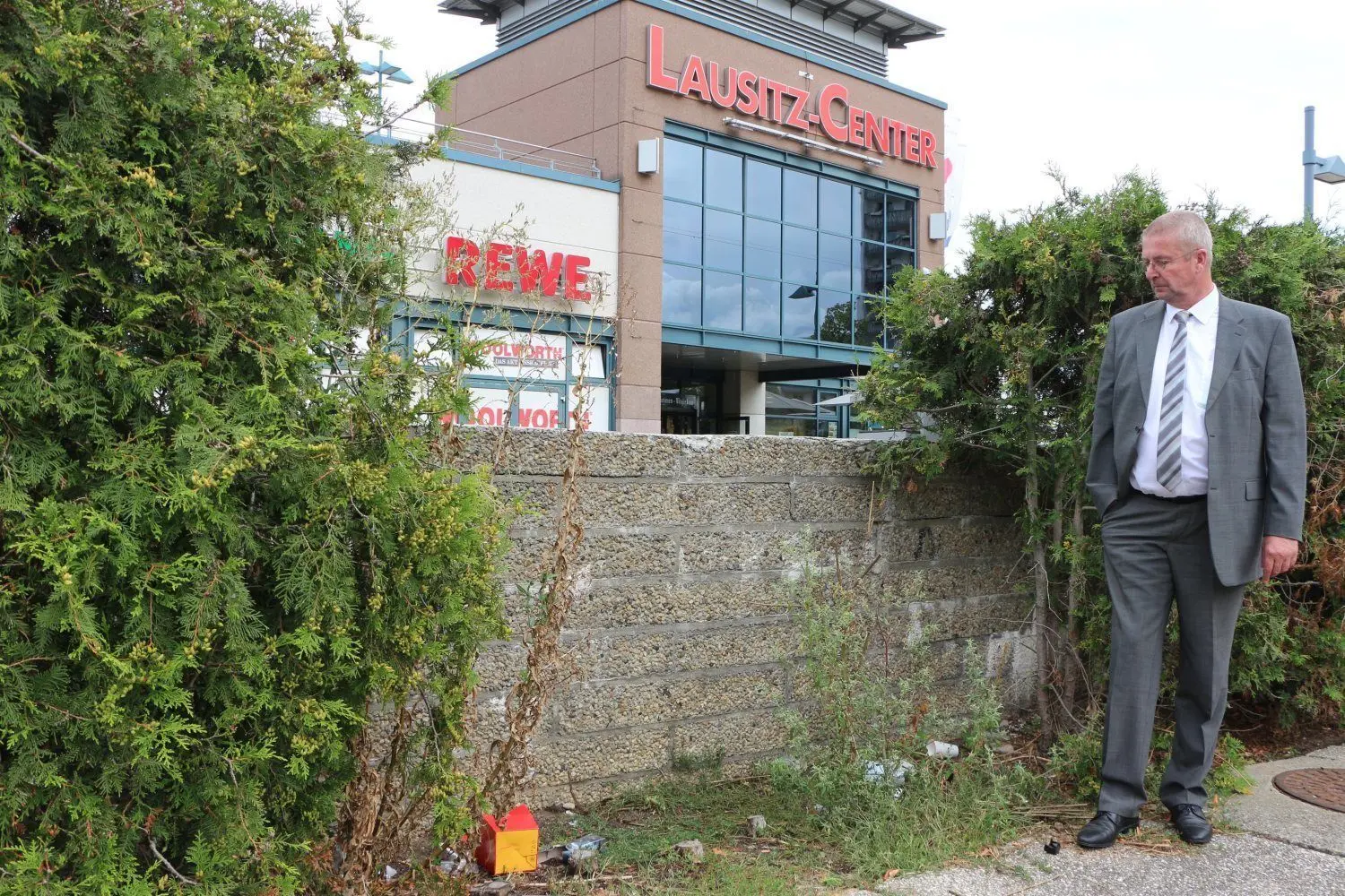 Müll und Dreck liegen regelmäßig hinter der Mauer vom Ehrenhain. Dieter Henke, Center-Manager vom Lausitz-Center, hat schon zusätzlich zwei Papierkörber aufstellen lassen.