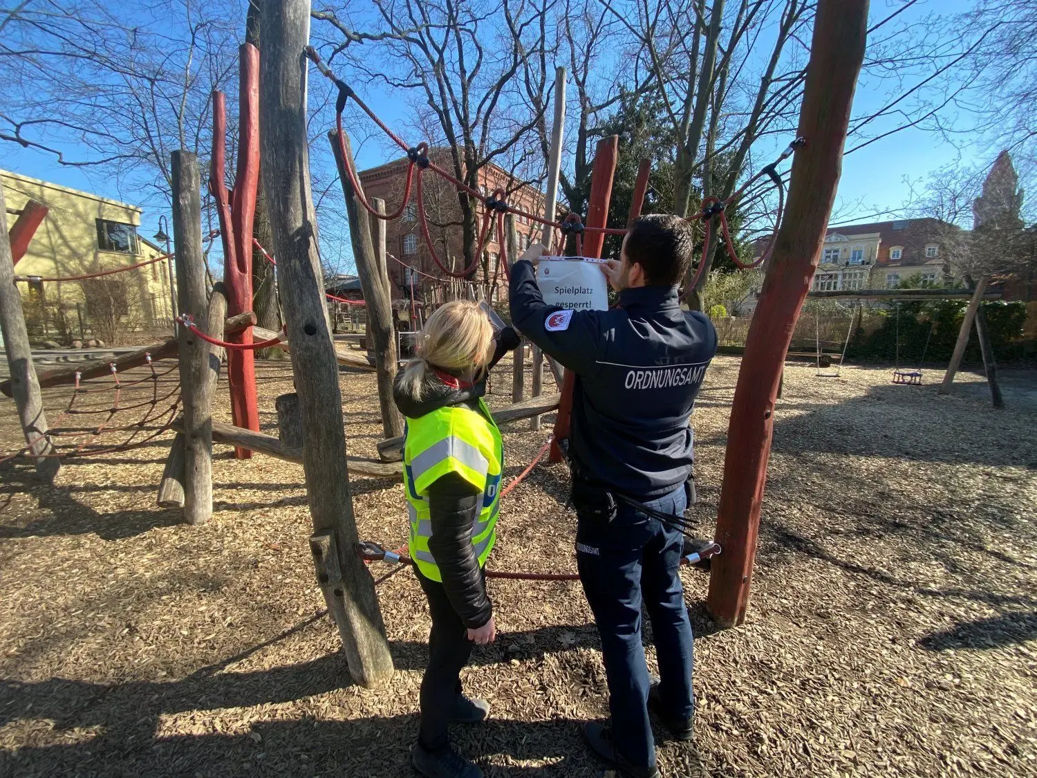 Ordnungsamt auf Streife:Tony Welzel und Michelle Marschall bringen im Puschkinpark ein Schild "Spielplatz gesperrt" an.