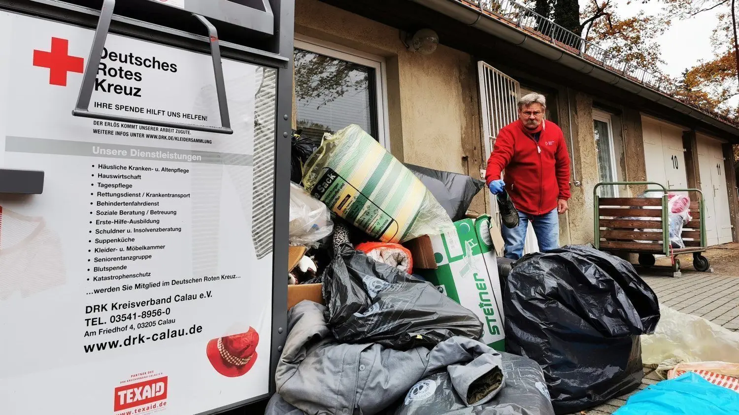 Manfred Günzel, Fahrdienstleiter des DRK Kreisverbandes Calau, zeigt die illegal entsorgten Müllberge am Kleidercontainer der Kleiderkammer des DRK Calau.