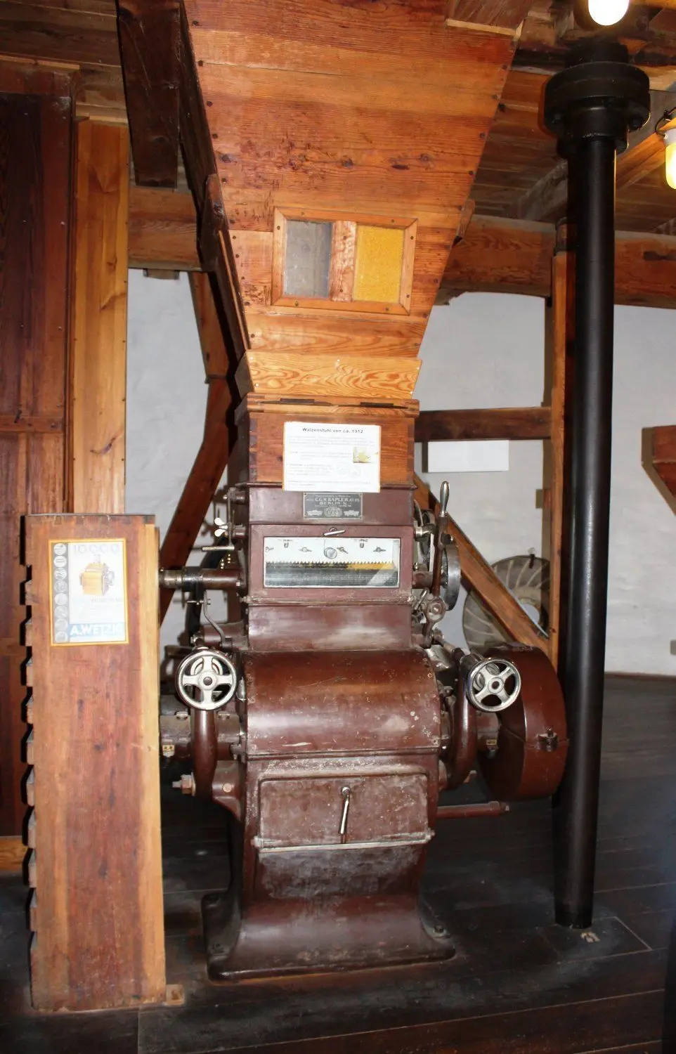 In der Kornmühle: links der Walzenstuhl aus dem Jahr 1912, rechts daneben die Königswelle, die die Energie der Flügel im Gebäude weiterleitet.