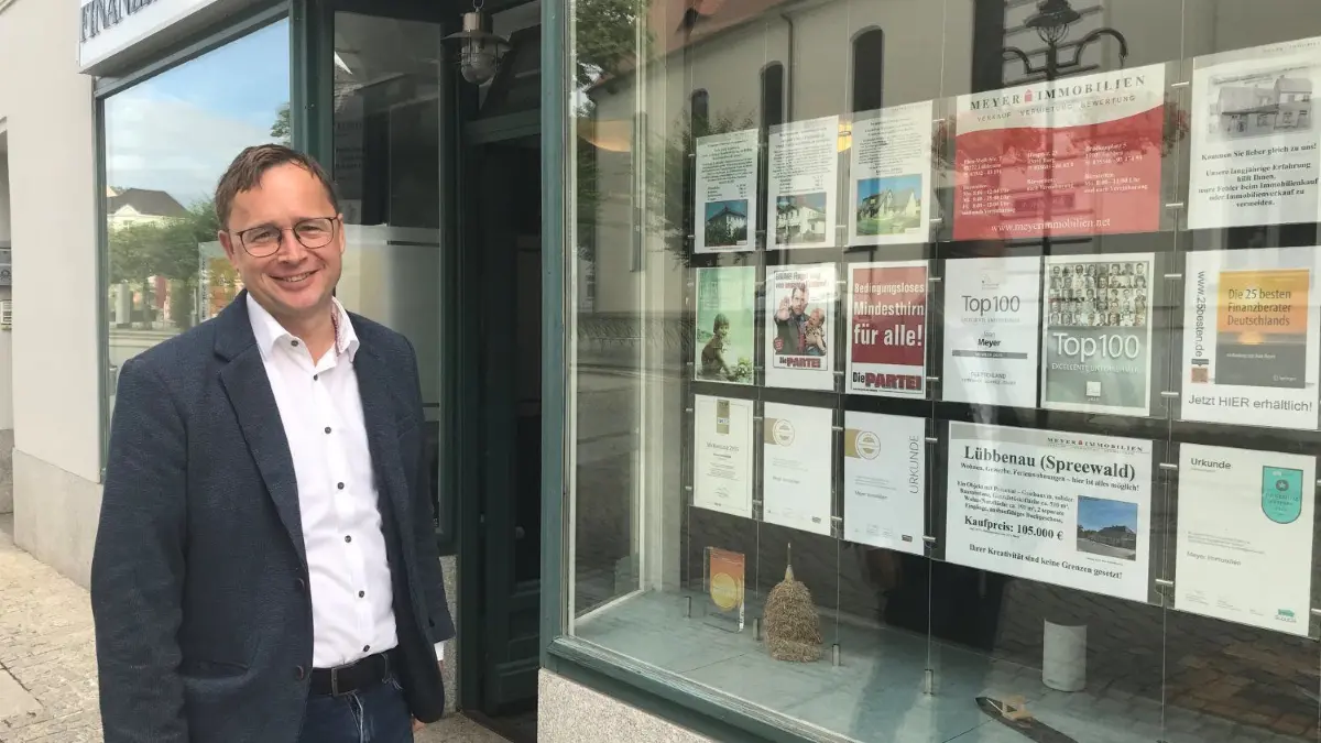 Der Lübbenauer Immobilienmakler Jean Meyer will mit kontroversen Aushängen zum Nachdenken anregen.
Makler und Millionär Jean Meyer hängt neben den üblichen Immobilieninseraten auch kontroverse Bilder und Statements zu Politik und Zeitgeist aus. Eine Version dieser Schaufensterdekoration hat für viel Kritik gesorgt.