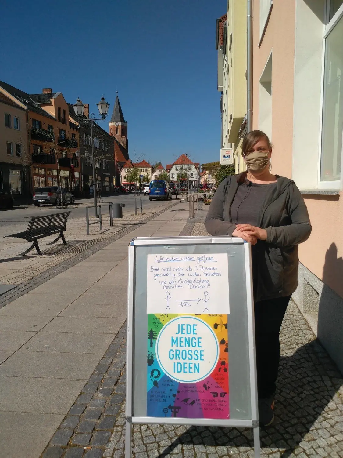Sonja Knospe, Angestellte der Buchhandlung Calau, trägt seit Mittwoch Mundschutz. Auf einer Tafel vor dem wiedereröffneten Laden hat sie Verhaltensregeln für ihre Kunden zusammengetragen.