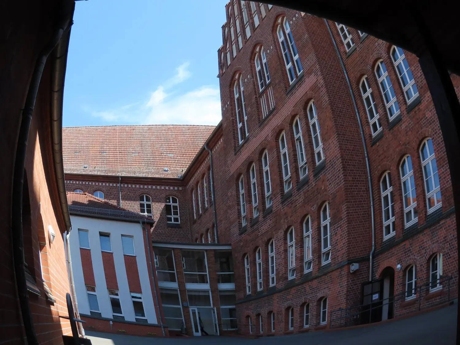 Blick über den Schulhof zum Eingang der Cafeteria, als die Tür im Sommer noch heil war.