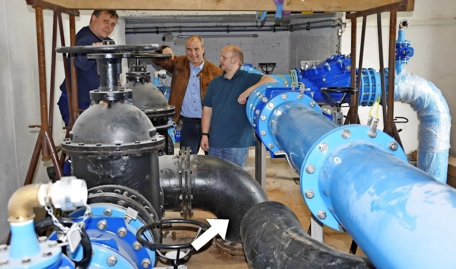 Die schwarze Stahlleitung (DN 400), die aus der Erde kommt (Pfeil), wird ersetzt, erst provisorisch durch eine DN-300-Leitung aus PE, in zweiter Phase durch eine DN-400 aus PE. Von links: Heiko Pirschel (Meister Trinkwasser), WAV-Verbandsvorsteher Maik Hauptvogel und Silvio Graf, Technischer Leiter.
