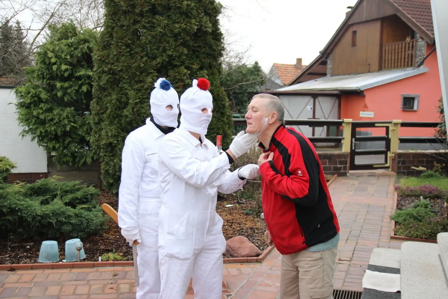 Jürgen Templin wird von den weißen Gestalten mit Mehl, Holzmesser und Hochprozentigem rasiert. Auch das gehört zum Wiednitzer Bärentreiben.