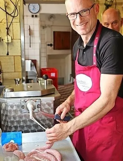 Schnipp-schnapp: Nachdem Fleischermeister Frank Sinapius das Bret mit einer Kolben-Füll-Maschine in den Schweinedarm gepresst hat, schneidet er die Wurstkette ab.