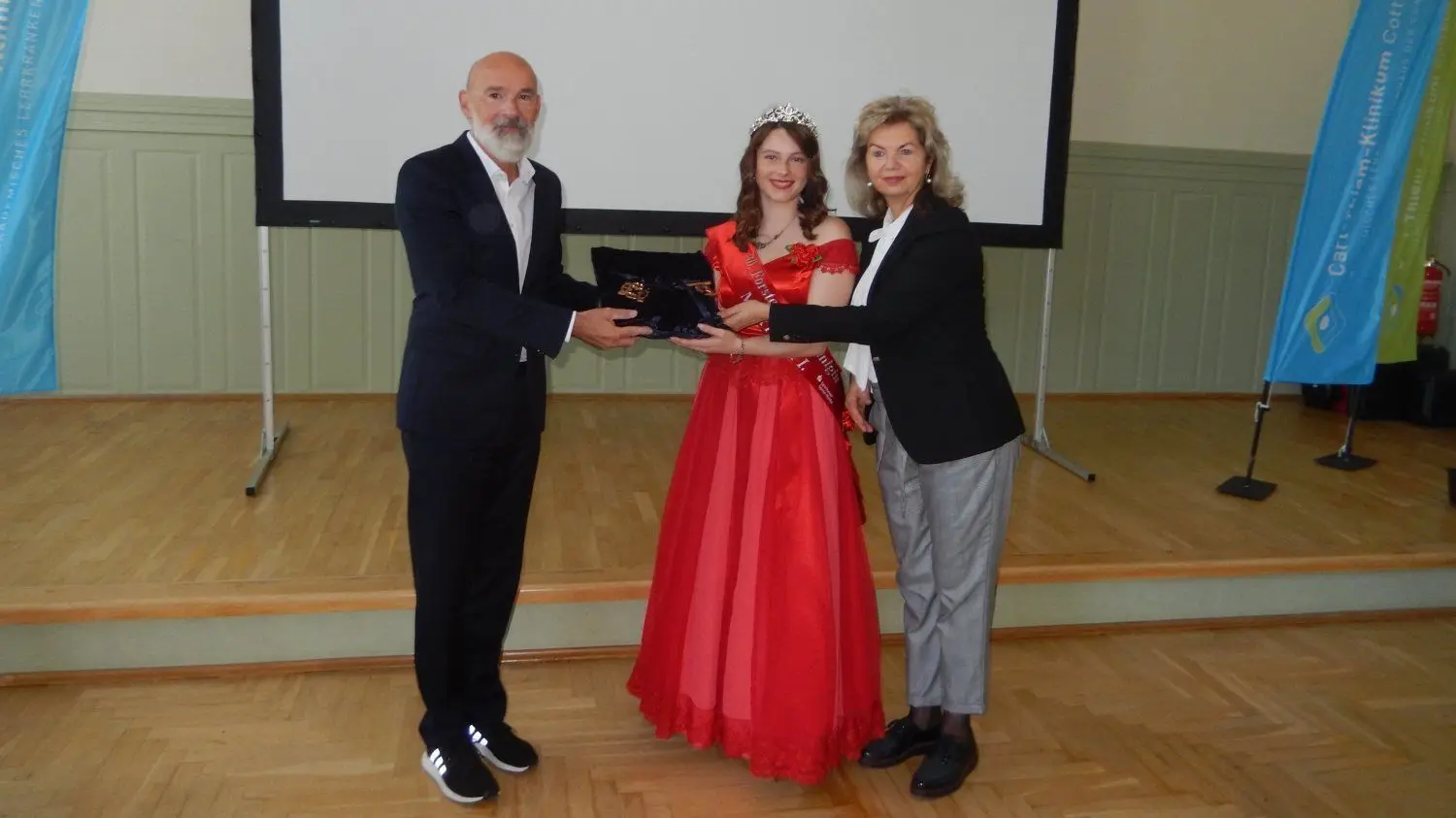 Dagmar Klinke, Geschäftsführerin der Forster Wohnungsbaugesellschaft (r.), überreicht zusammen mit Rosenkönigin Martyna I. den Schlüssel der Pflegeschule an CTK-Geschäftsführer Dr. Götz Brodermann.