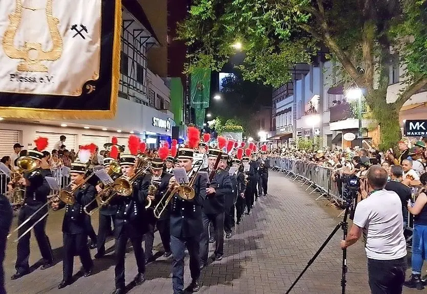 Das Jugendblasorchester aus Plessa marschiert bei der Oktoberfestparade in Blumenau weit vorn im Zug. Die Zuschauer jubeln und winken.
