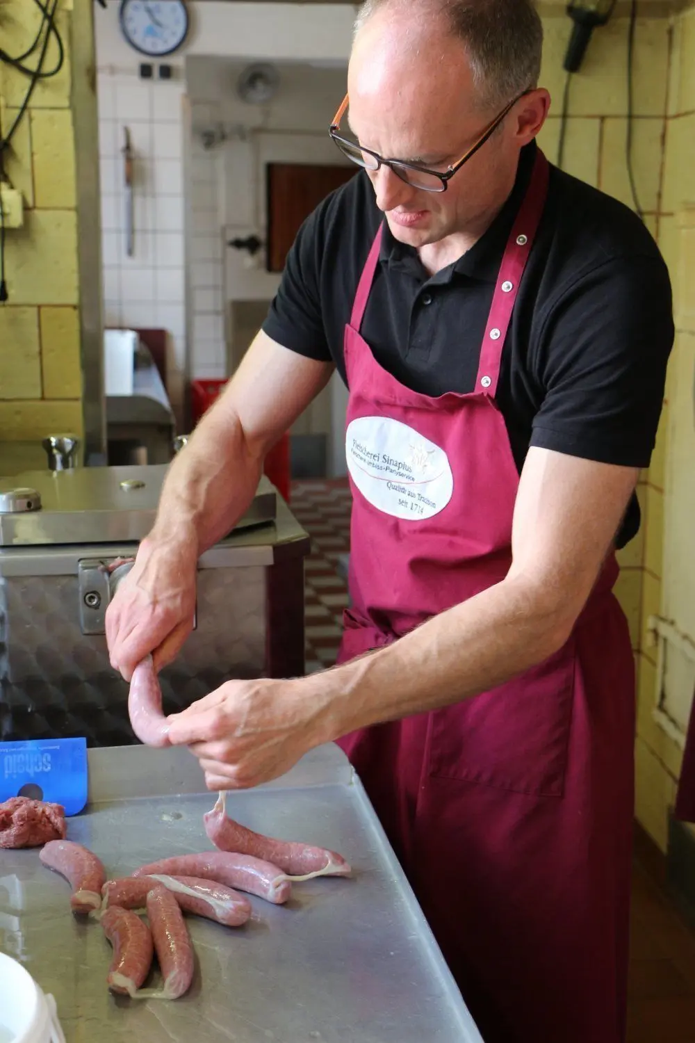 Konzentriert bei der Arbeit: Fleischermeister Frank Sinapius presst das Bret mit einer Kolben-Füll-Maschine in den Schweinedarm.