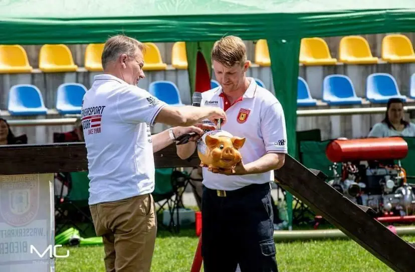 Bürgermeister Waldemar Locke (l.) füttert das Sparschwein der Feuerwehr, das die Kameraden beim Oldiecup für die Spendenaktion aufgestellt haben.